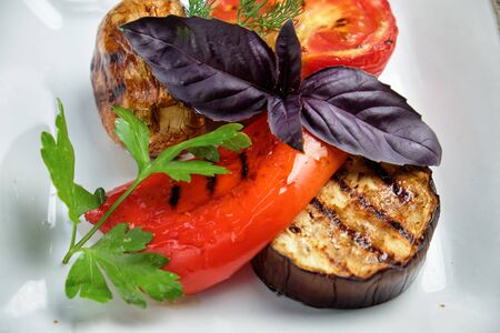 Grilled vegetables on a white plate on a dark wooden background. catering menuの写真素材