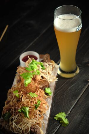 Glass of cold beer with appetizer on wooden boards on a dark wooden background. catering menuの写真素材