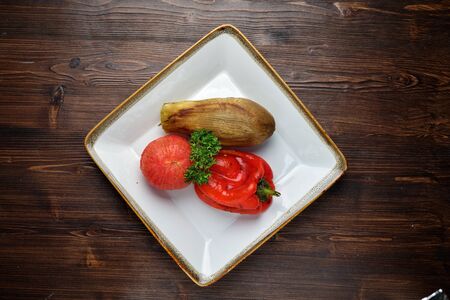 Grilled vegetables on a white plate on a dark wooden background. catering menuの写真素材
