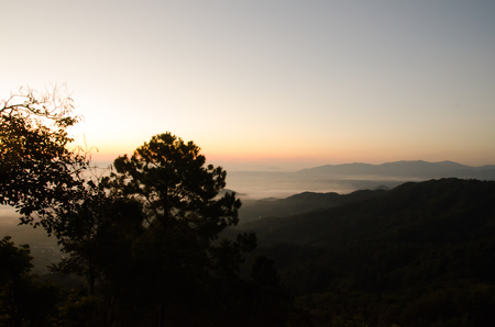 A lot of mist and sunrise behind the mountain at the northern Thailand.の写真素材