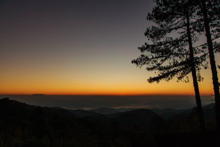 Beautiful sunrise sky and silhouette pine tree on top of mountainの写真素材