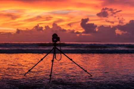 Silhouette camera with tripod on sunset sky at beachの写真素材