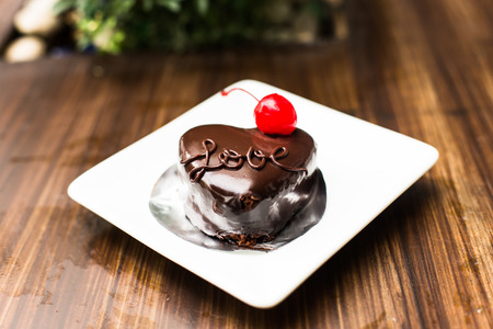 Love heart shape of chocolate cake with red cherryの写真素材