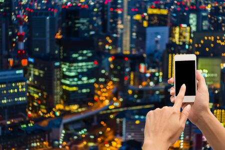 Hand hold blank smartphone on blue city light backgroundの写真素材