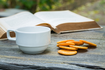 Coffee and old book in garden with biscuitの写真素材