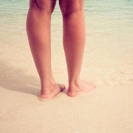 Vintage filter woman foot on tropical sand beachの写真素材