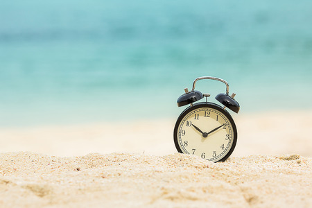 Alarm clock on white tropical sand beach backgroundの写真素材
