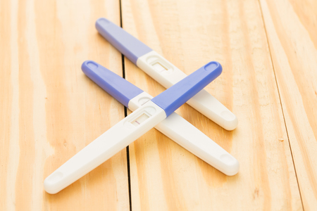 Positive pregnancy tester on wood backgroundの写真素材