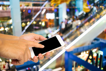 Hand using smartphone on blur shopping mall backgroundの写真素材