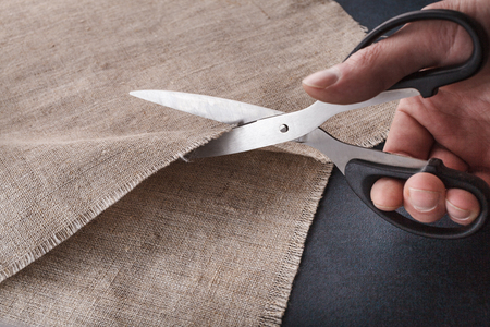 A man's hand cuts linen cloth with tailor's scissors.の写真素材