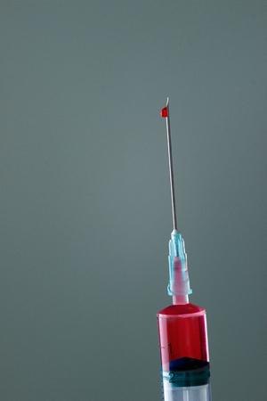 The end of the syringe with a needle filled with liquid, on a neutral background.の写真素材