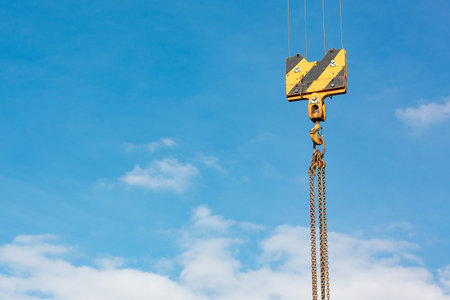 Crane load hook against the sky with trails and chain.