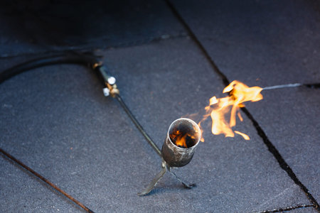 Laying waterproofing by heating roofing felt with fire.