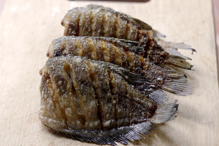 fried snakeskin gourami fish on chopping blockの写真素材