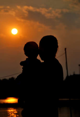 silhouette of mother and her daughter with sunriseの写真素材