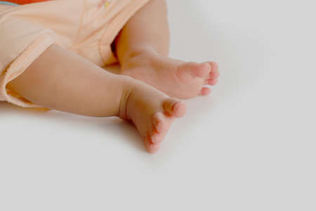 feet  of eight month old baby sitting on white boardの写真素材