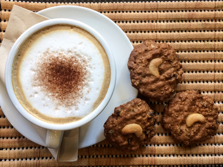 hot cappuchino coffee with cookie on wooden table, vintage and retro styleの写真素材
