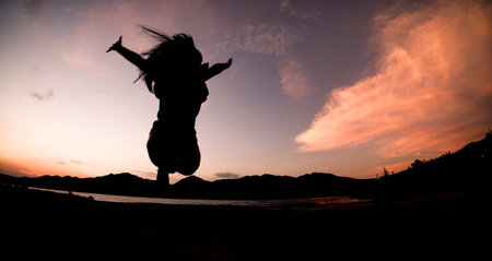 Silhouette, happy jumping Shadow girl Jump on the orange sky in the evening