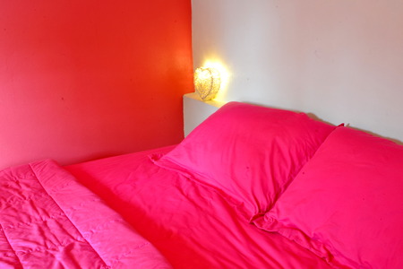 Bed in pink bed linen in roomの写真素材