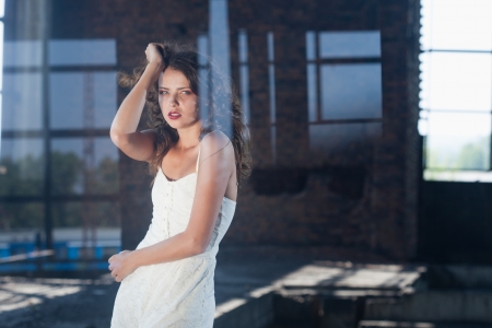 Young gorgeous brunette posing against the backdrop of a building with large windowsの写真素材