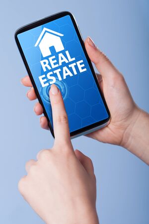 Man presses a touch screen smart phone with the symbol of real estate . Business, technology, internet concept.の写真素材