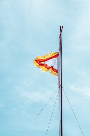 A red-yellow flag flutters against a blue sky in the backgroundの写真素材