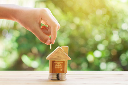 House placed on coins. hand that is coin down the house. Indicates the growth of home and finance. planning savings money of coins to buy a home concept property mortgage and investment for a house.の写真素材