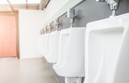 Men's room with white porcelain urinals in line. Modern clean public toilets with tiles . Comfort male toilet urinal concept.の写真素材