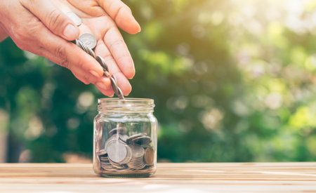 The hand is pouring coins into the jar. planning savings money of coins to buy a home concept...