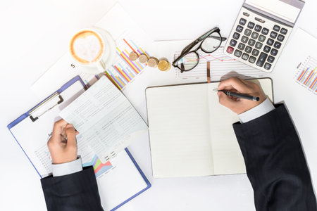 Male manager putting his ideas and writing business plan at workplace,man holding pens and Bank money book, making notes in documents, on the table in office concept for property, mortgage and invest.の写真素材