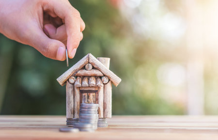House placed on coins. hand that is coin down the house. Indicates the growth of home and finance. planning savings money of coins to buy a home concept property mortgage and investment for a house.の写真素材