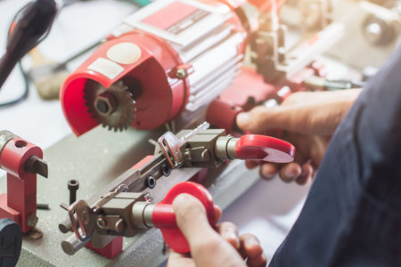 Locksmith in workshop makes new key. Professional making key in locksmith. Machine production of...