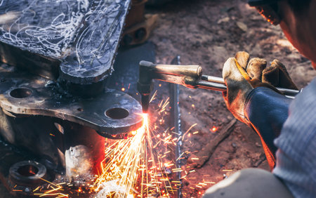 Close up hand heavy industrial worker is working on metal work factory process by Cutting sheet steel with gas cutting machine cutting thick steel in boilermakers workshop.の写真素材