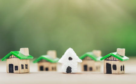 white house in among Green houses for real estate. planning savings money of coins to buy a home concept for property, mortgage and real estate investment. for saving or investment for a house.