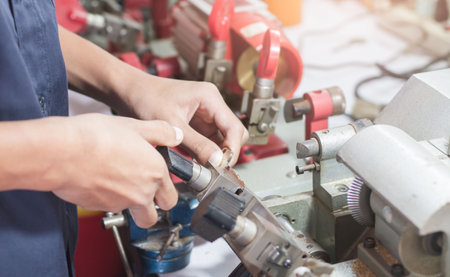 Locksmith in workshop makes new key. Professional making key in locksmith. Machine production of...