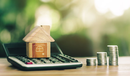 House is placed on the calculator and coins placed on table. concept calculating to buy a home. planning savings money of coins to buy a home concept for property, mortgage, real estate to buy a home.の写真素材