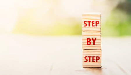 The word step by step on wooden cubes. Achievement or progress in business career. Business growth, career growth or goal concept.の写真素材