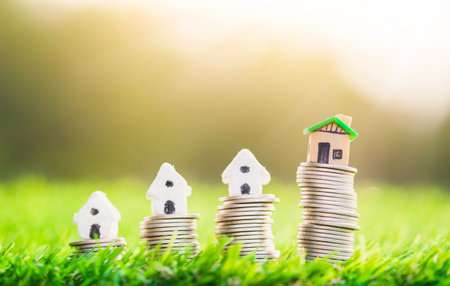 House placed on coins and coins place on the grass is ladder. planning savings money of coins to buy a home concept concept for property ladder, mortgage and real estate investment.の写真素材
