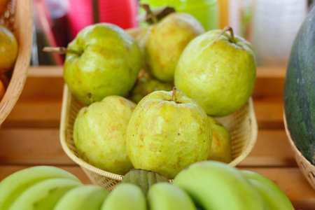 guava In wood basket on wood table or shelf at the market street in Thailand. Select focus.