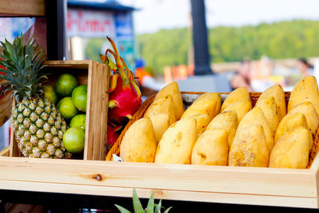Yellow mangoes,pineapple, lime on wood basket and shelf at market street in Thailand.の写真素材