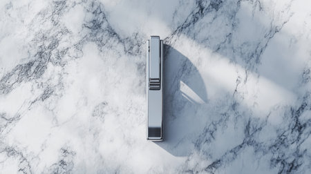 A sleek silver stapler is positioned on a marble surface, showcasing modern design and minimal aesthetics. Ideal for office or workspace visuals.の素材