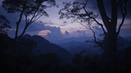 A peaceful mountain landscape at twilight showcasing silhouettes of trees against a dramatic sky filled with clouds and fading light.の素材