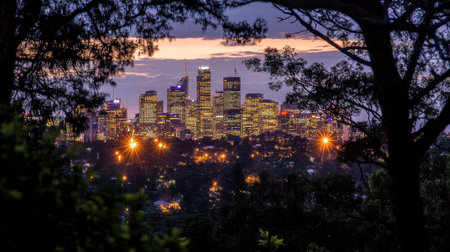 A stunning view of a vibrant city skyline at dusk, highlighted by illuminated buildings. The natural framing of trees adds depth to the urban landscape.の素材