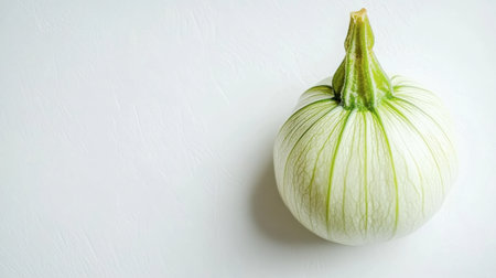 A fresh white onion with green streaks sits on a light background, perfect for food-related projects or culinary themes highlighting healthy ingredients.の素材