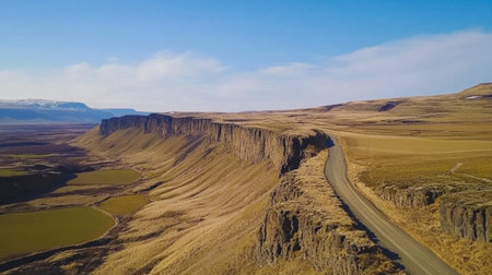 Breathtaking aerial view of a serene road winding through majestic mountain landscapes under a clear blue sky, inviting travel and exploration.の素材