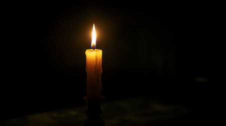 A single candle burning in a dark room, its light casting soft shadows on the walls.の素材