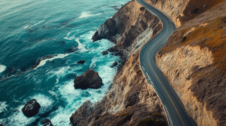 A scenic coastal road hugging the edge of a cliff, with waves crashing against the rocks below.の素材