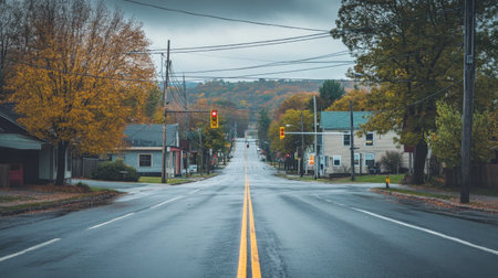 A small-town intersection with a single traffic light controlling the peaceful, empty road.の素材