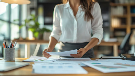 A businesswoman standing at a desk, preparing financial documents for an important meeting.の素材