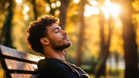 A man with short, curly hair sitting on a park bench, his hair catching the sunlight as he enjoys a moment of peace.の素材
